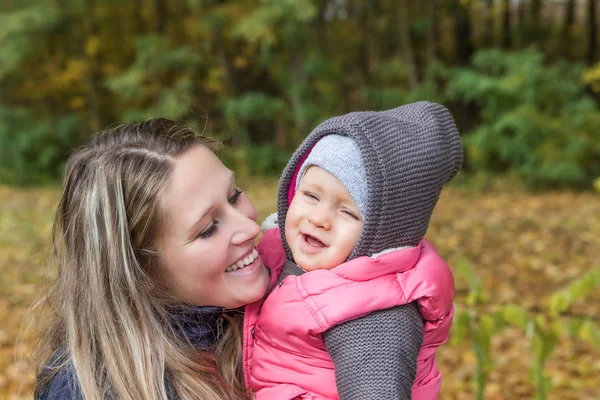 Mãe sorridente está olhando para sua filha bebê ao ar livre — Fotografia de Stock