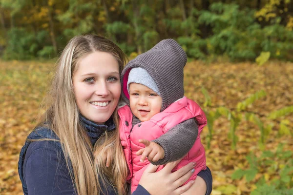 Leende ung mor med sin baby dotter i armar — Stockfoto