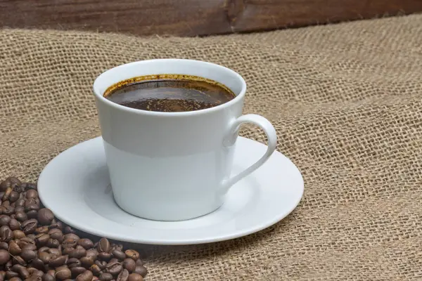 Šálek kávy s rozptýleným kávová zrna — Stock fotografie