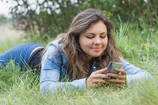 Menina adolescente morena legal vendo seu telefone inteligente ao ar livre — Fotografia de Stock