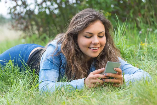 Sonriente adolescente utilizando el teléfono inteligente al aire libre —  Fotos de Stock