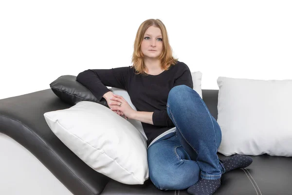 Pensive jovem mulher está sentado em um sofá preto e branco — Fotografia de Stock