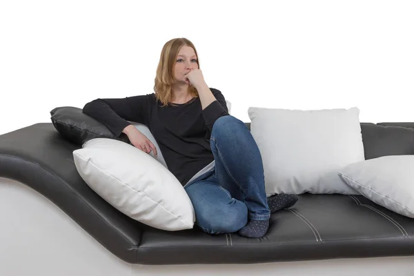 Traurige junge Frau sitzt auf einer schwarz-weißen Couch — Stockfoto