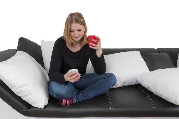 Giovane donna sta usando smartphone in possesso di una tazza rossa — Foto Stock