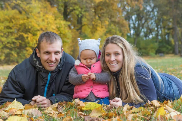 Happy young parents with her child are lying on the ground outdo — Stock Photo, Image