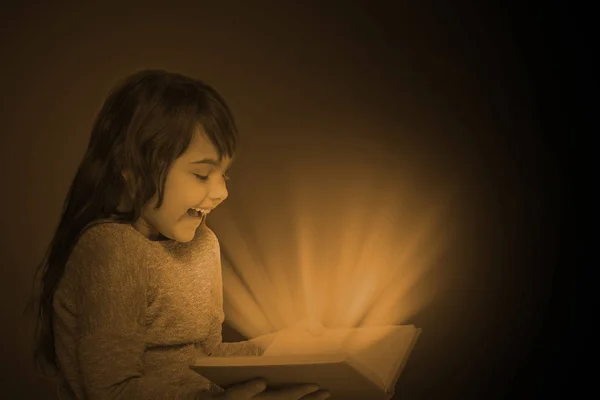 Foto oscura de una niña sosteniendo un libro abierto — Foto de Stock