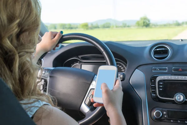 年轻的司机女人正在使用智能手机在车里 — 图库照片
