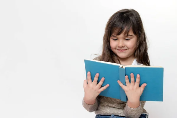 Front view of smiling little girl reading a book — Stock Photo, Image