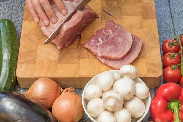 Vista frontal de la mujer rebanando carne en un primer plano de madera —  Fotos de Stock