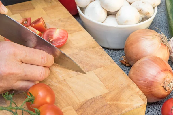 Vista lateral de la mujer cortando un tomate en una tabla de madera —  Fotos de Stock