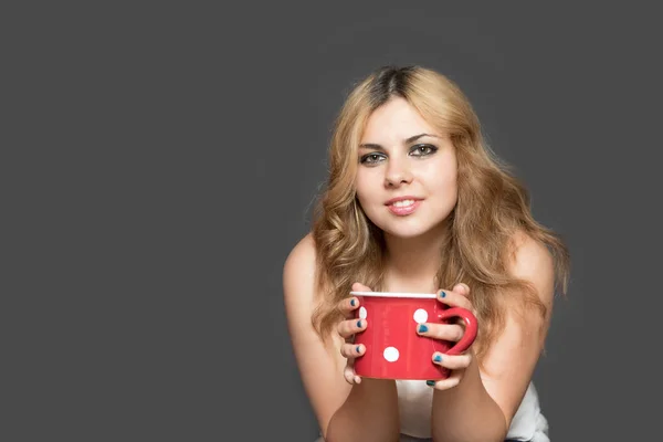 Diente sonriente joven mujer está sosteniendo rojo manchado taza — Foto de Stock