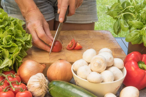 Vista anteriore di affettare un pomodoro su una tavola di legno — Foto Stock