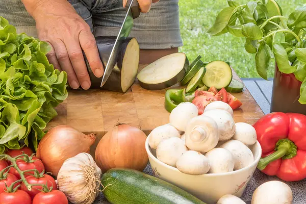 Frontansicht des Schneidens einer Aubergine auf einem Holzbrett — Stockfoto