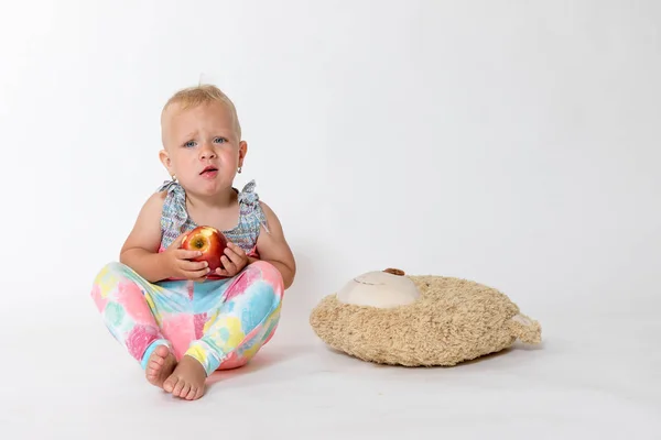 Toute la figure de la jeune fille en colère assis et tenant pomme rouge — Photo