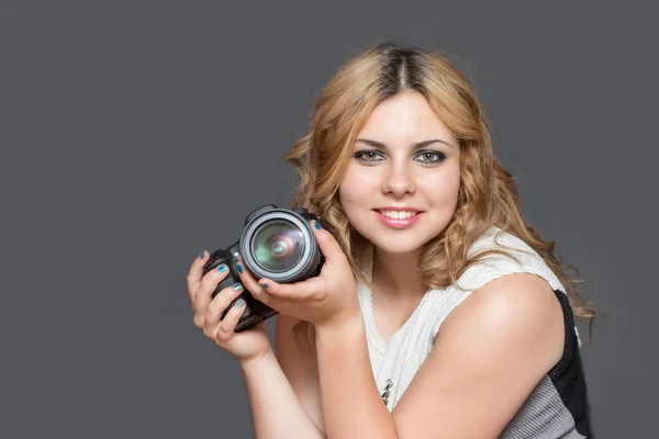 Lachende jonge vrouw houdt een camera met beide handen — Stockfoto