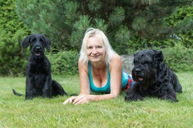 Gülümseyen kadın köpek yavrusu ve dev Blac yetişkin köpek arasında yatıyor