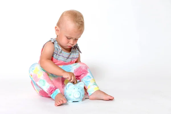 Kleuter meisje is het gooien van munten in het opslaan van piggy bank — Stockfoto