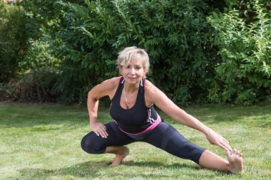 Gülümseyen kıdemli kadın onun uzanan bahçede yapıyor