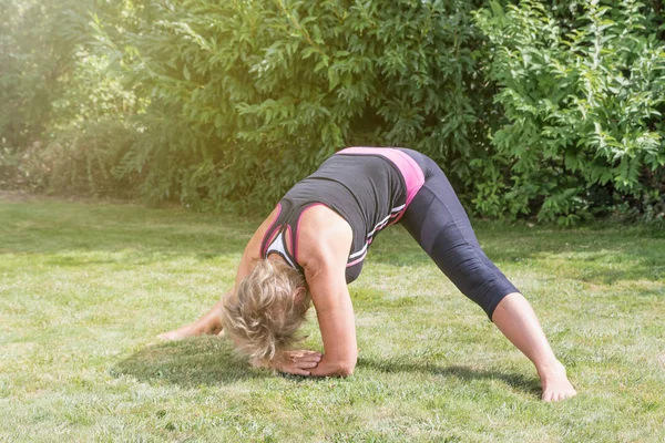 Senior woman exercising in wide-legged forward bend