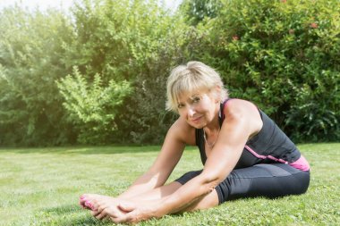 Bacaklarını açık havada germe yapıyor sarışın kadın kıdemli