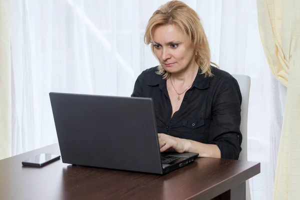 Smiling middle aged woman is working in the office at home. — Stock Photo, Image