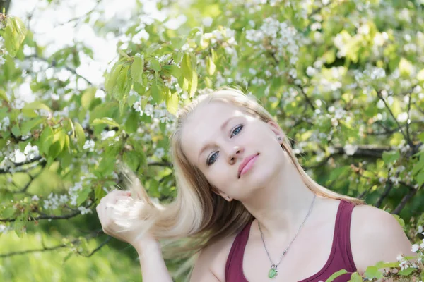 Lächelnde junge blonde Frau spielt mit ihren Haaren. — Stockfoto