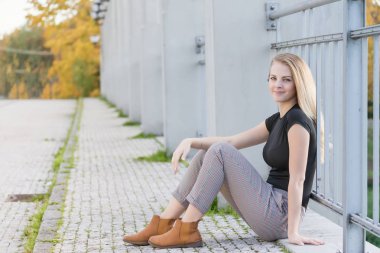 Güzel genç kız köprüde oturuyor.