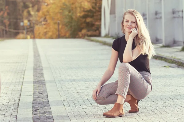 Attractive young girl squatting outdoors