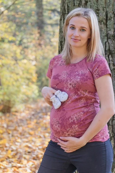 Jeune femme enceinte en montrant des chaussons de bébé — Photo