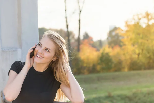 Glimlachend meisje staat op de brug te bellen en kijkt over — Stockfoto