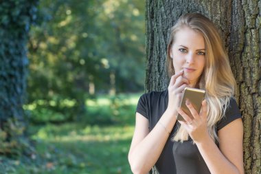 Düşünceli çekici kız akıllı telefon kullanıyor.