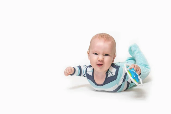 Sourire bébé garçon est couché sur fond blanc tenant un jouet . — Photo