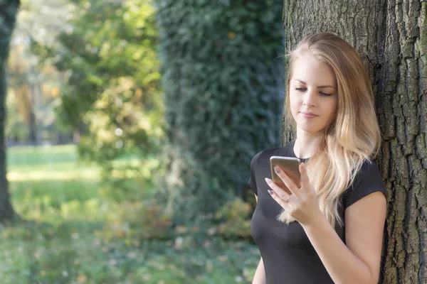 Chica joven es reflexivo mirando en la pantalla del teléfono inteligente —  Fotos de Stock