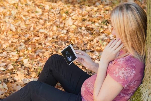 Pregnant young woman is looking at space shot of her unborn chil — Stock Photo, Image