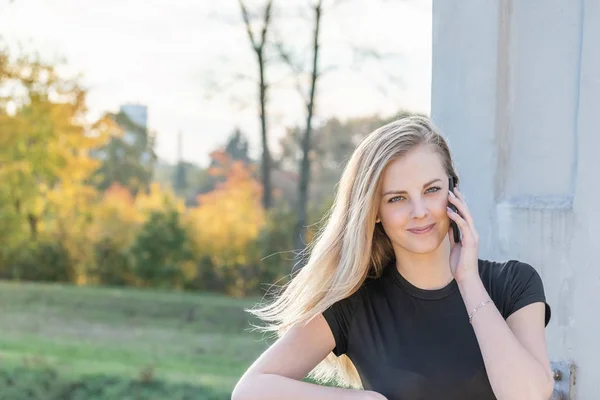 Telefonisches langhaariges Mädchen lächelt in die Kamera — Stockfoto