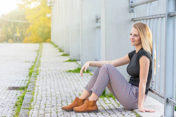 Seitenansicht eines lächelnden jungen Mädchens, das auf der Brücke sitzt — Stockfoto