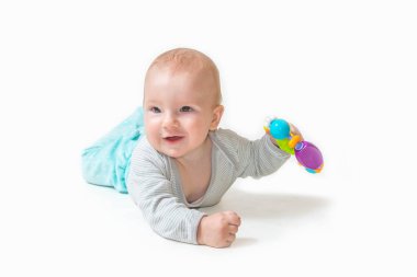 Oyuncak oğlan kameraya yalan söylüyor ve gülümsüyor elinde oyuncak tutuyor hepsi beyaz arka planda.