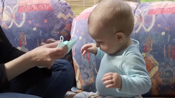 Lucu bayi kecil mencoba untuk menghancurkan topeng wajah pelindung sekali pakai. — Stok Video