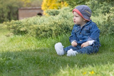 Saldırgan kızgın erkek bebek çimlerin üzerinde oturuyor. Fotoğrafta kullanabileceğiniz yeterli boş yer var..