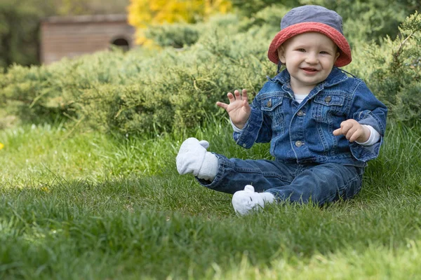 Liebenswert Lächelnder Kleiner Junge Sitzt Draußen Auf Dem Gras Und — Stockfoto