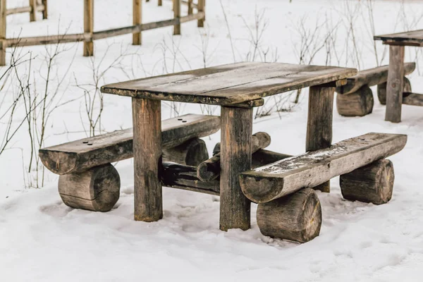 Eski ahşap masa ve bankların üzerinde kar kış sonunda. Bahar geliyor.