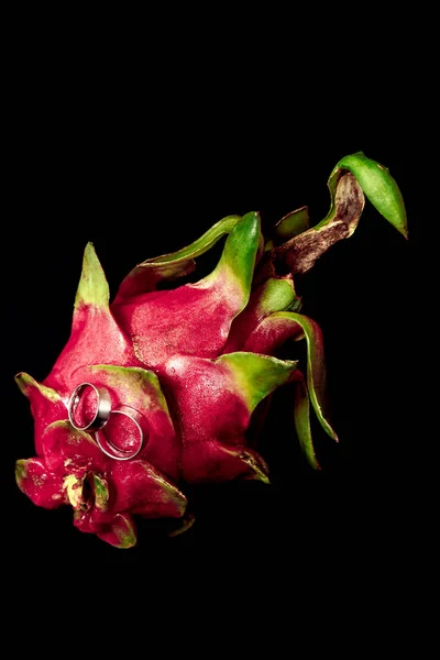 Beyaz altından alyanslar yakın plan, siyah arka plan egzotik meyveler.