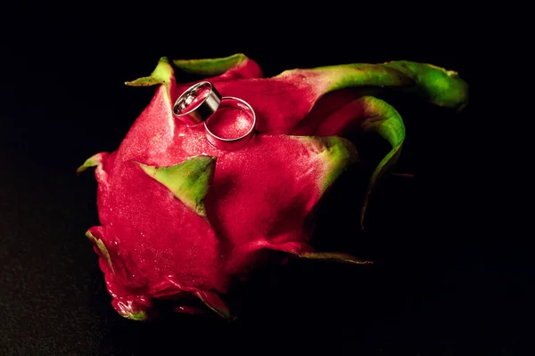 Alyanslar egzotik meyvelerde beyaz altın renginde, yakın plan, siyah arka plan