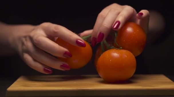 Closeup of woman hands opens a tomato from a branch on wooden board in a modern kitchen. Healthy diet. . — Stock Video