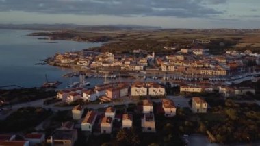 İtalya, Sardinya 'da güzel bir köy. Sahilde güneş doğuyor, yatları park ediyor.