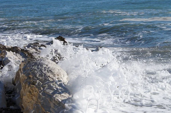 Die Gischt der Meereswelle, die gegen die weißen Felsen am Ufer schlägt. — Stockfoto