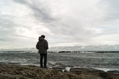 Bir adam shore, bulutlu, soğuk, Sonbahar, Hazar Denizi'nin kıyısında Dağıstan.
