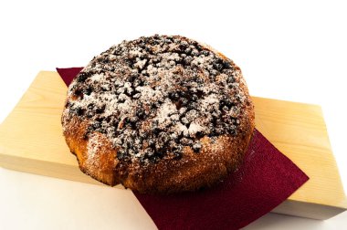 Ev yapımı hamur işleri - bir yuvarlak pasta Siyah frenk üzümü, kalın bir ahşap tahta üzerinde bard peçeteye koydu beyaz bir arka plan üzerinde beyaz şeker tozu ile serpilir ile.