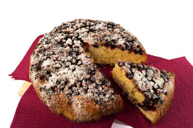 Bir dilim kesilmiş ve bordo renk beyaz zemin üzerinde bir kağıt çanta koymak Siyah frenk üzümü ile ev yapımı pasta.