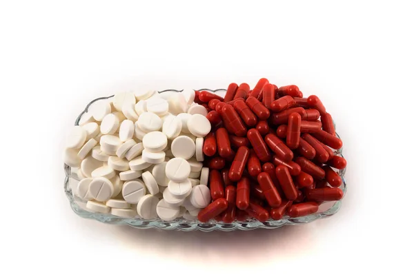 赤カプセルと白い背景の上のガラス板に積み上げられた白い錠剤 — ストック写真
